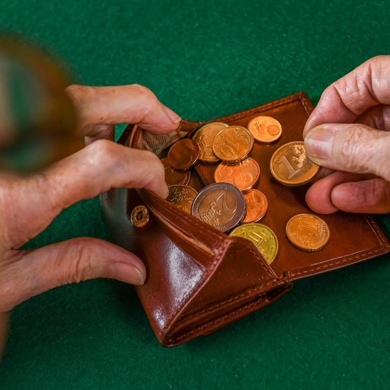 Eine Frau zählt Münzen in ihrem Portemonnaie.