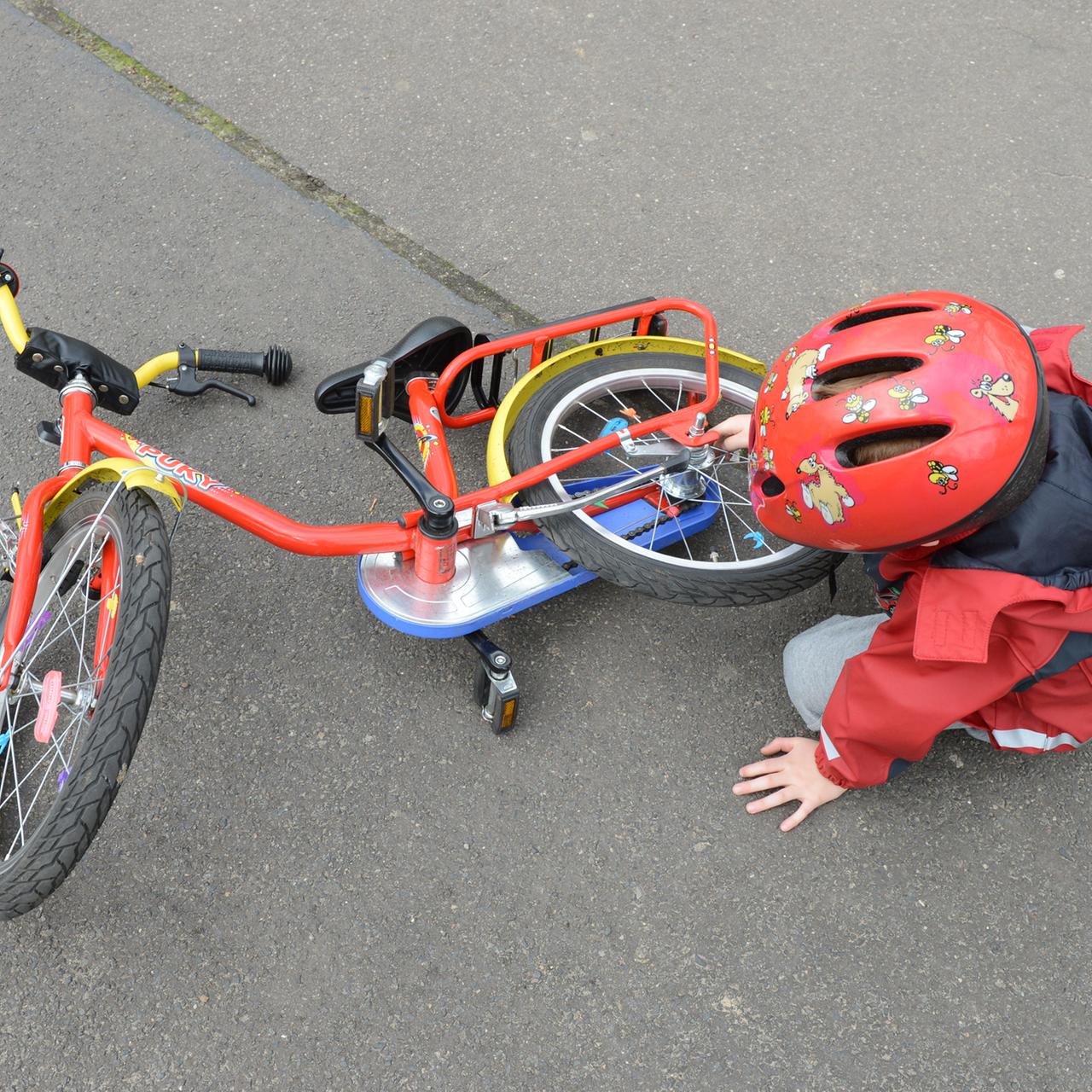 Ein Kind sitzt neben seinem Fahrrad auf der Straße.