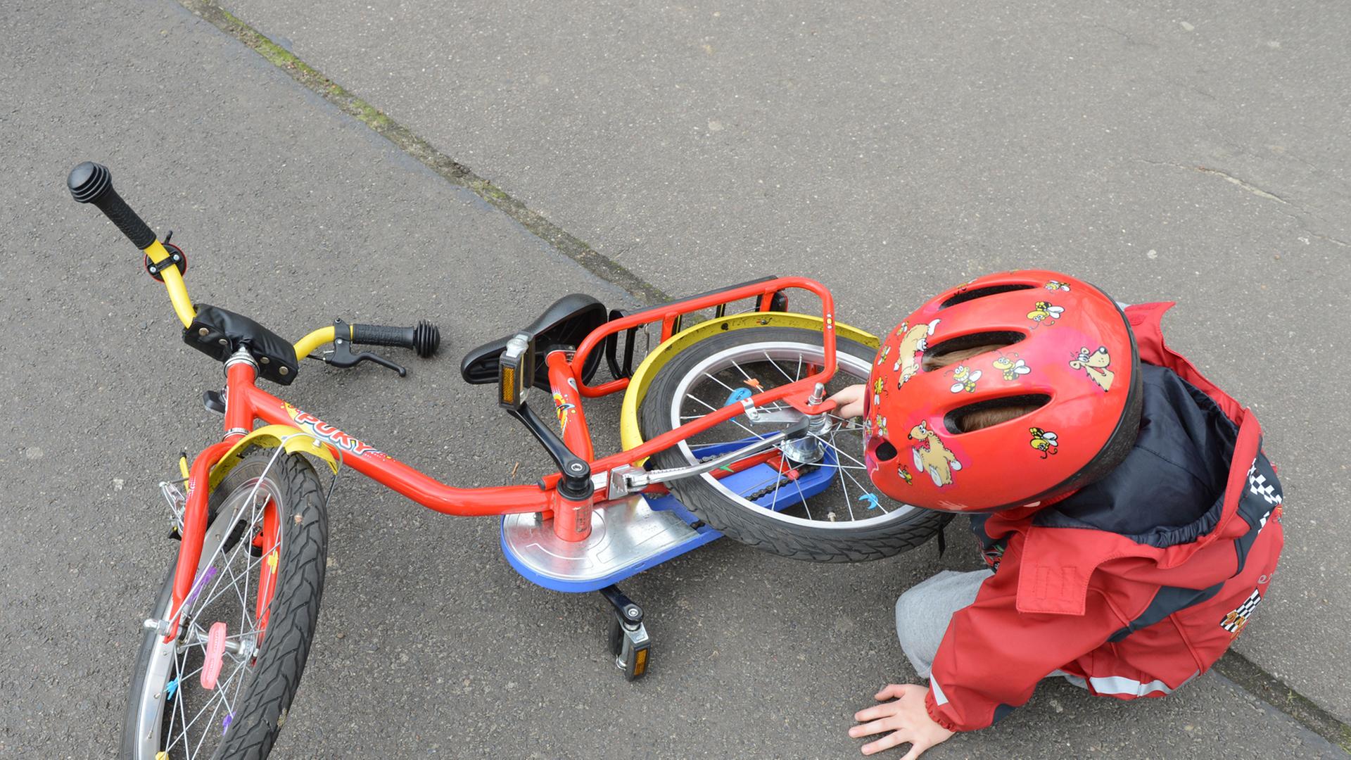 Ein Kind sitzt neben seinem Fahrrad auf der Straße. Ein Kind sitzt neben seinem Fahrrad auf der Straße.