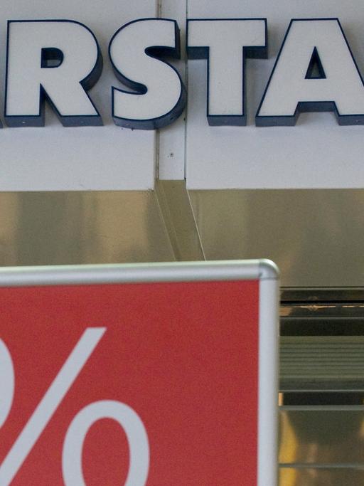 Eine Passantin geht am Dienstag (08.06.vor dem Karstadt-Warenhaus in Münster an einem Plakat mit dem Aufdruck "Reduziert" vorbei.