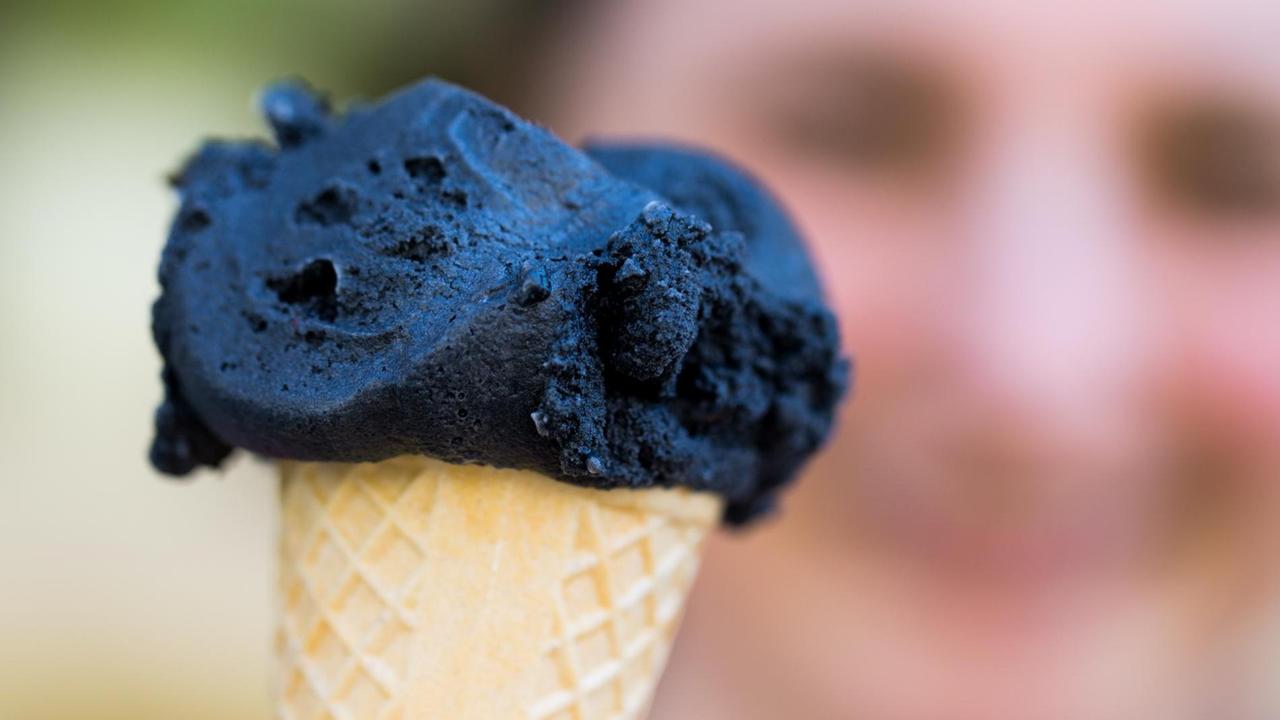 Eine Kugel schwarzes Eis in einer Waffel vor verschwommenem Hintergrund. Eine Kugel schwarzes Eis in einer Waffel vor verschwommenem Hintergrund.