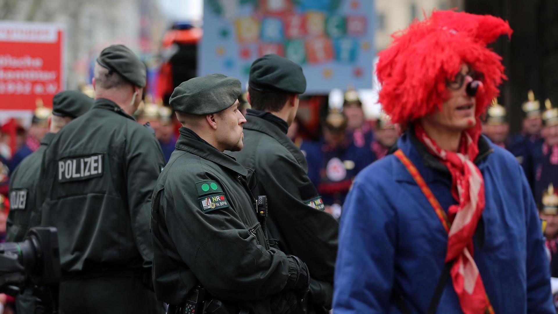 Polizisten stehen am 16.02.2015 in Köln (Nordrhein-Westfalen) neben Karnevalisten am Zugweg.