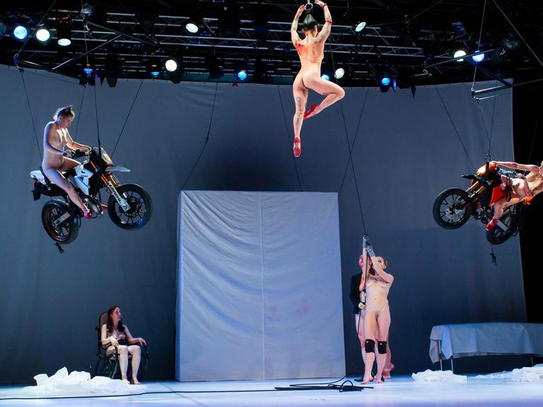 Künstlerinen schweben im Stück "Tanz" nackt auf Motorrädern