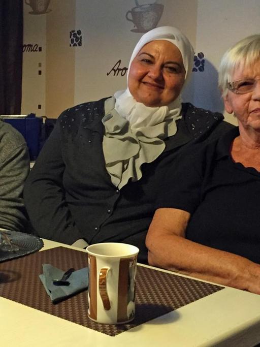 Saad und seine Mutter sitzen gemeinsam mit Edeltraut Söhnel in einer Küche bei Kaffee.