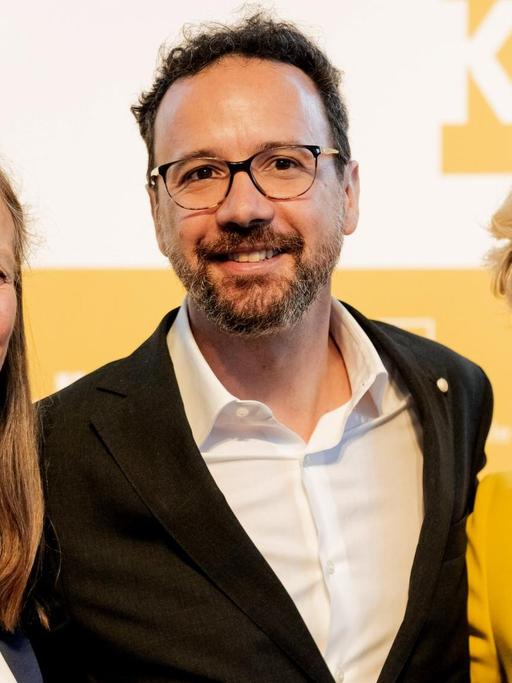 Monika Grütters präsentiert am 22.6.2018 die neue Berlinale-Doppelspitze: Marietta Rissenbeek und Carlo Chatrian. Alle drei blicken lachend in die Kamera.