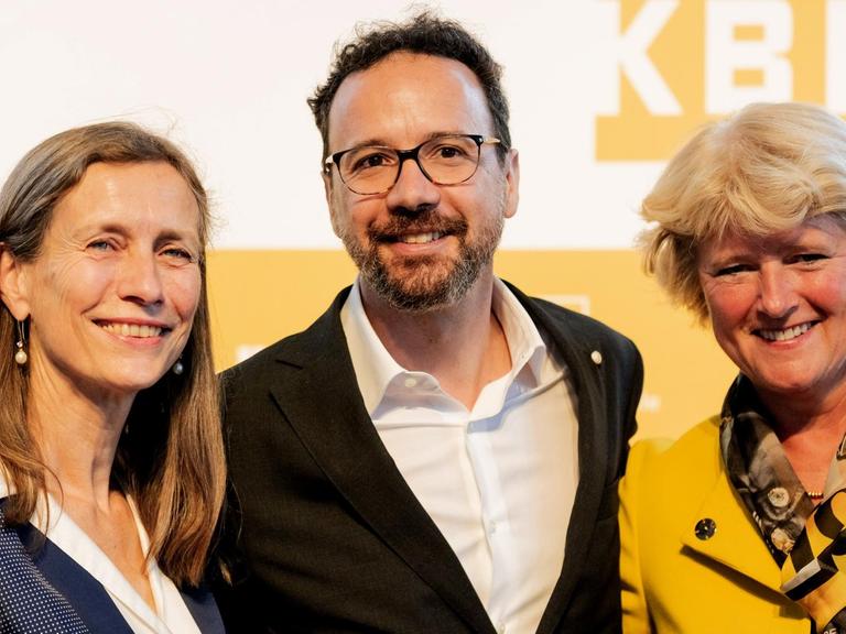 Monika Grütters präsentiert am 22.6.2018 die neue Berlinale-Doppelspitze: Marietta Rissenbeek und Carlo Chatrian. Alle drei blicken lachend in die Kamera.