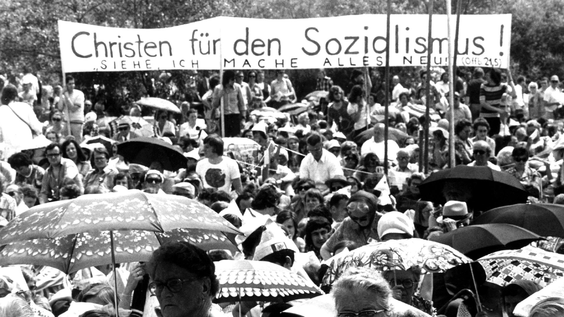 Mit einer Schlusskundgebung unter freiem Himmel ging am 15. Juni 1975 der 16. Deutsche Evangelische Kirchentag in Frankfurt am Main zu Ende. Ein Plakat mit der Aufschrift "Christen für den Sozialismus - Siehe, ich mache alles Neu!" ist zu sehen.
