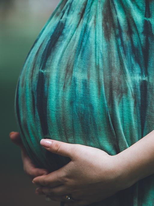 Eine schwangere Frau hält ihren Babybauch. Ein Feature über Geburten, Hebammen und Geburtshäuser.