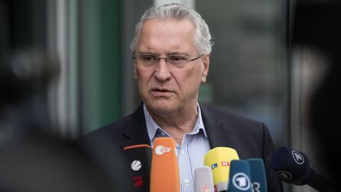 Bayerns Innenminister Joachim Herrmann (CSU) äußert sich in Berlin, vor ihm die Mikrofone mehrerer Sender.