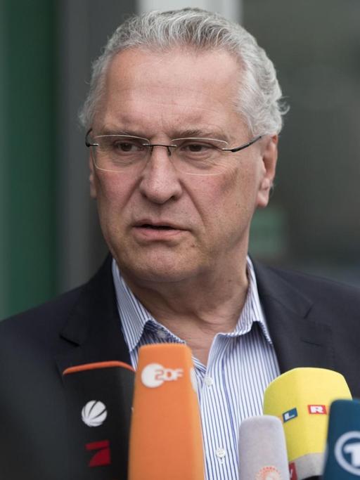 Bayerns Innenminister Joachim Herrmann (CSU) äußert sich in Berlin, vor ihm die Mikrofone mehrerer Sender.