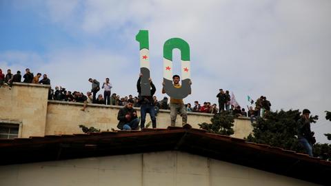 Protestierende in Idlib halten am 15. März 2021 eine 10 in die Höhe zum 10. Jubiläum des Ausbruchs der syrischen Revolution