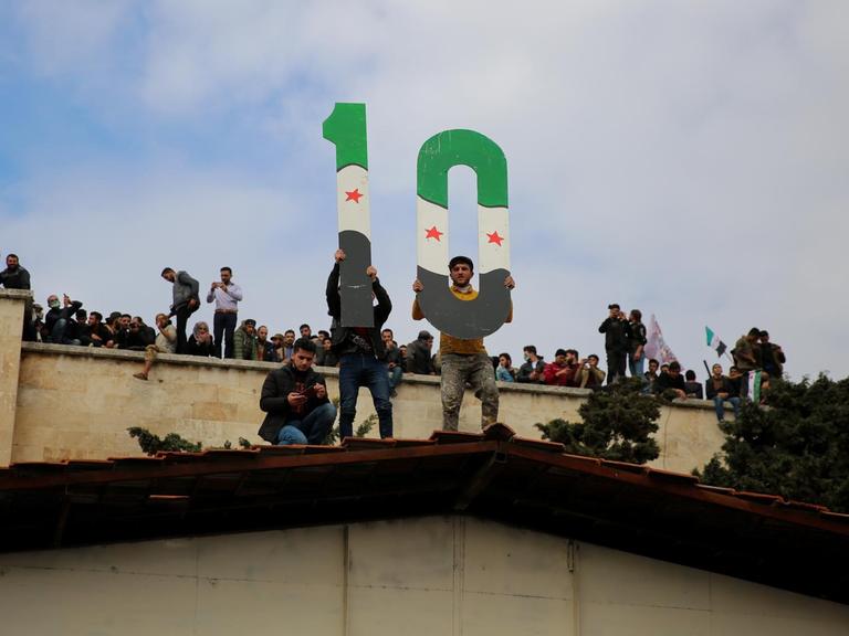 Protestierende in Idlib halten am 15. März 2021 eine 10 in die Höhe zum 10. Jubiläum des Ausbruchs der syrischen Revolution