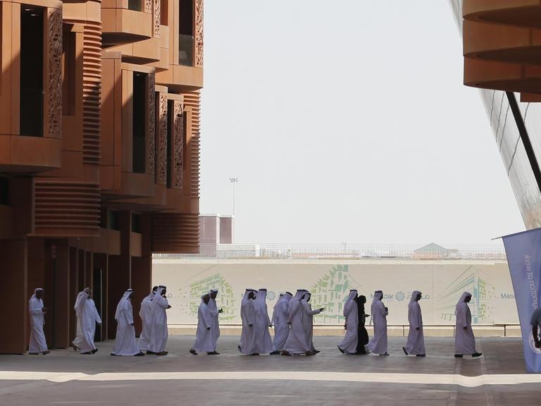 Emiratis walk in Masdar City, on the outskirts of the rich Emirate of Abu Dhabi, on October 7, 2015. Masdar City is a high-density, pedestrian-friendly development where current and future renewable energy and clean technologies are showcased, marketed, researched, developed, tested and implemented.