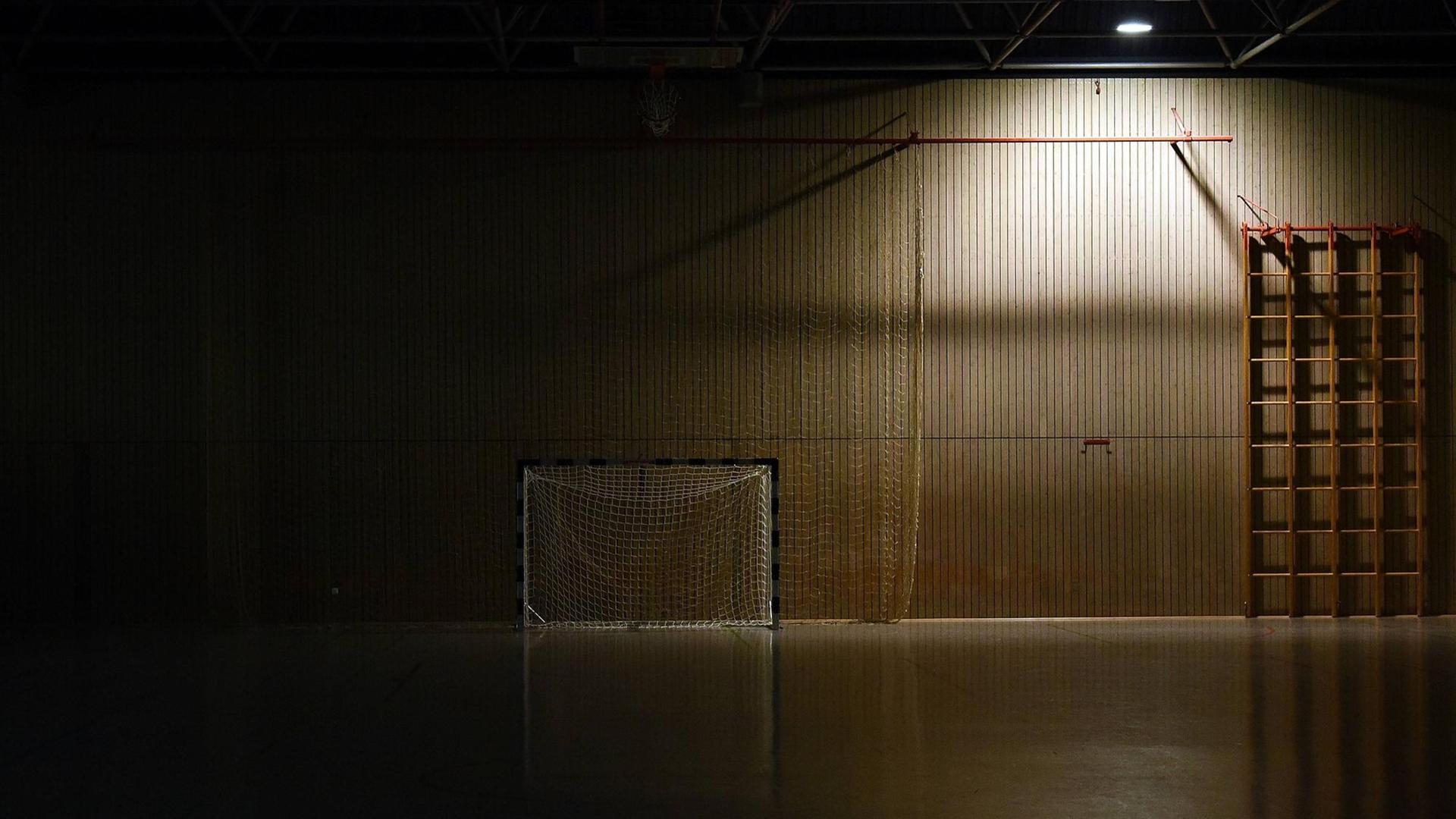 Ein dunkle und leere Sporthalle mit einem Handball-Tor.
