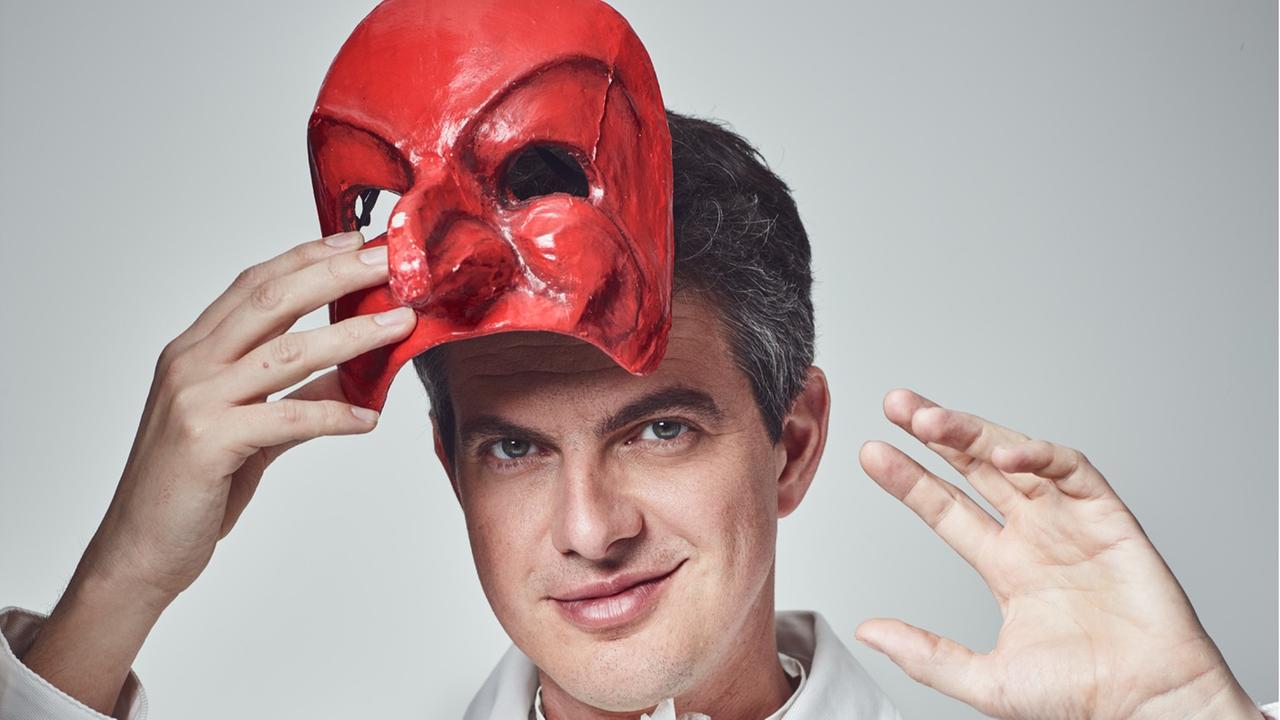 Der Countertenor Philippe Jaroussky hält eine rote Maske in der Hand.
