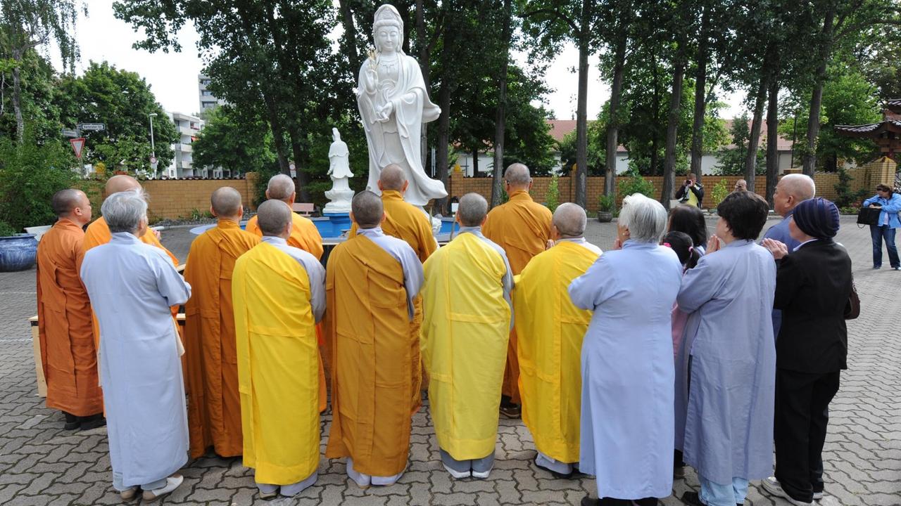 Mönche und Nonnen beten vor einer Avalokiteshvara-Statue, die vor dem buddhistischen Kloster Pagode Vien Giac in Hannover aufgestellt wurde.