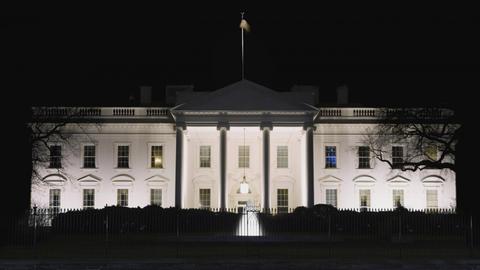Das White House in Washington DC bei Nacht, in einem Fenster scheint Licht.