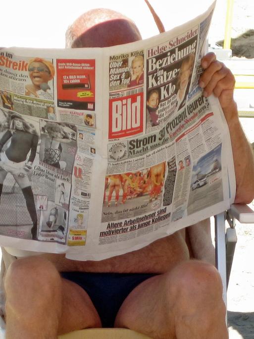 Ein deutscher Urlauber liest die Bild-"Zeitung" am Strand.