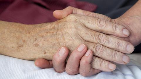 15.07.2010, Nordrhein-Westfalen, Deutschland - Hospiz. Die Hand einer Pflegerin haelt die Hand eines sterbenden Mannes. (QF, ältere, älterer, berühren, Berührung, bettlägerig, europäisch, Fürsorge, fürsorglich, Hände, häusliche Pflege, Menschenwürde, menschenwürdiges Sterben, Nähe, trösten) 00X110715D001.JPG MODEL RELEASE: YES,RELEASE: