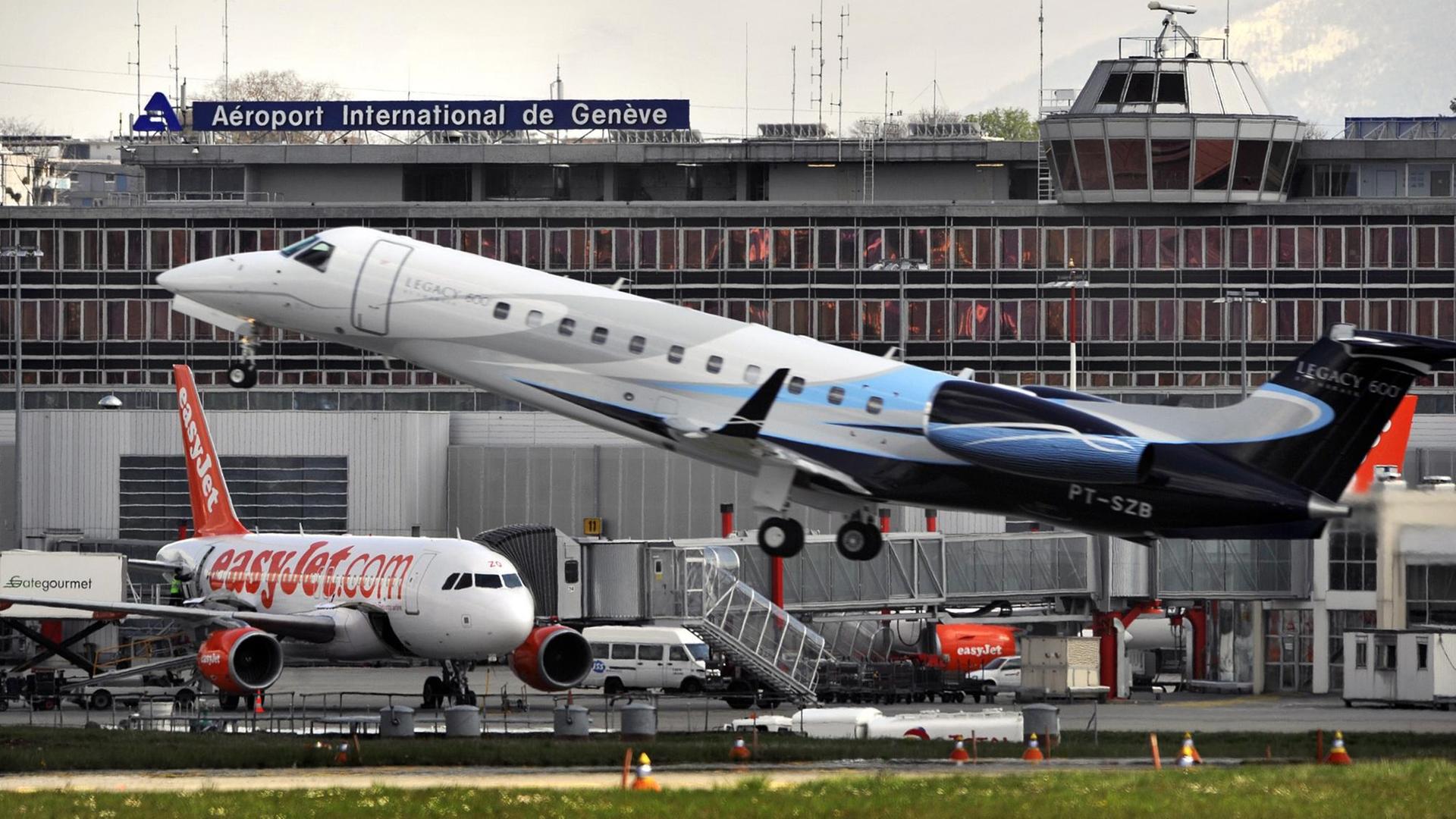 Blick auf ein Geschäftsflugzeug, das vor dem Gebäude des Internationalen Flughafens Genf abhebt.