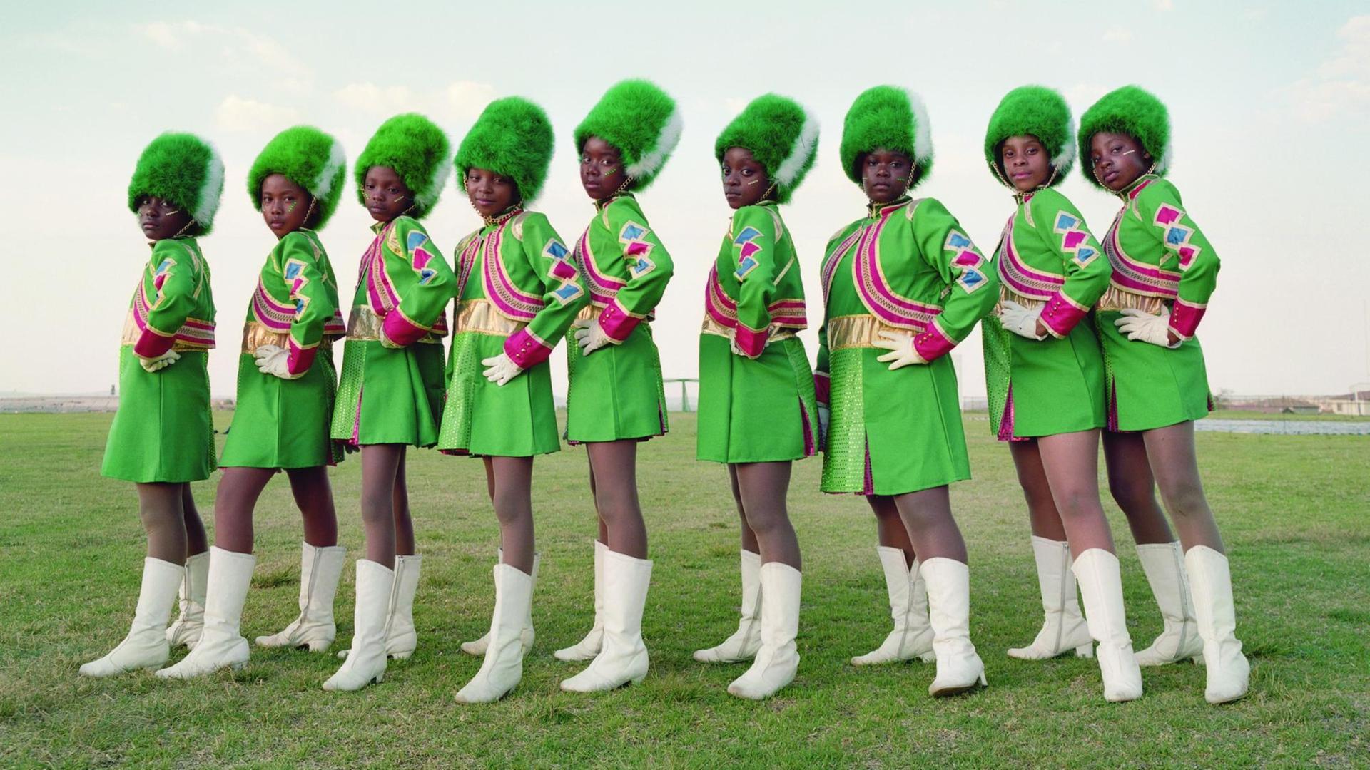 Neun Frauen in knallgrünen Kostümen.