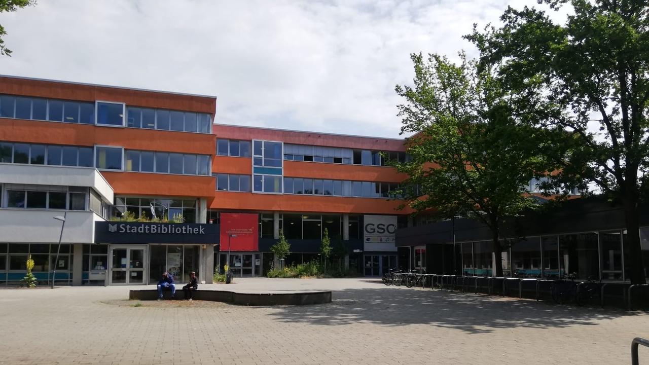 Blick auf ein rotes Schulgebäude mit Schulhof und Bibliothek.