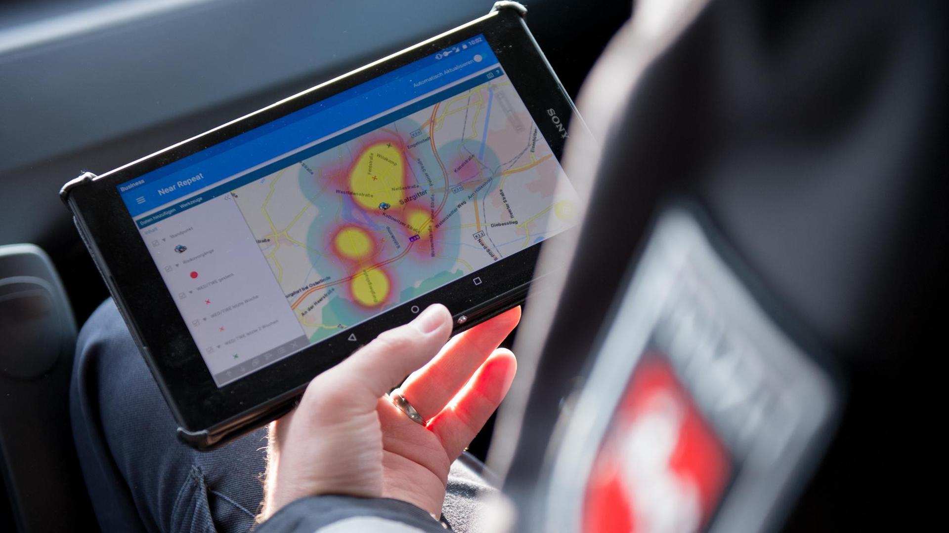 Ein Kommissar hält ein Tablet-PC mit der Einbruchs-App "Premap" in der Hand.