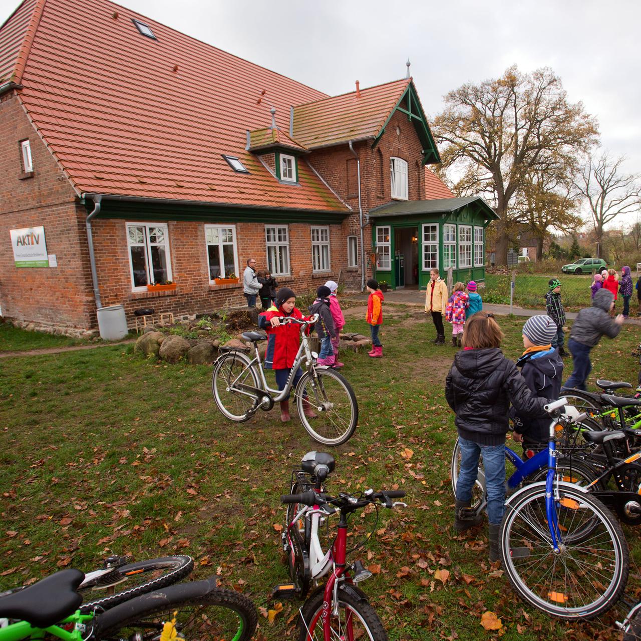 Schüler der privaten Grundschule in Bröbberow stellen auf der Wiese vor dem Schulgebäude ihre Fahrräder ab.