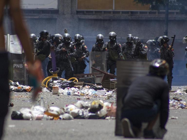 Sicherheitskräfte bewachen am 20.07.2017 eine von Demonstranten blockierte Straße in Caracas (Venezuela). Viele Läden und Geschäfte der Hauptstadt blieben angesichts des eines Generalstreiks geschlossen. Aufgerufen wurde der Streik von der Opposition. Ihr Ziel: die von Präsidenten Maduro geplante Verfassungsreform zu verhindern. Straßen wurden von Demonstranten blockiert. Foto: Rayner Pena/dpa | Verwendung weltweit