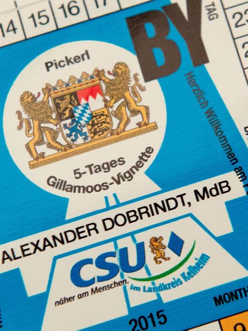 Eine fiktive Maut-Plakette mit der Aufschrift "Alexander Dobrindt - 5-Tages Gillamoos-Vignette" liegt in Abensberg (Bayern) beim politischen Gillamoos-Frühschoppen auf einem Tisch.