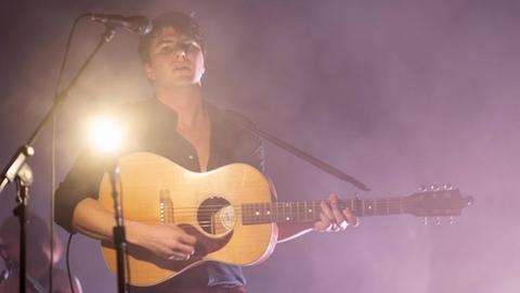 Singer-Songwriter Faber mit Gitarre auf der Bühne im Scheinwerferlicht