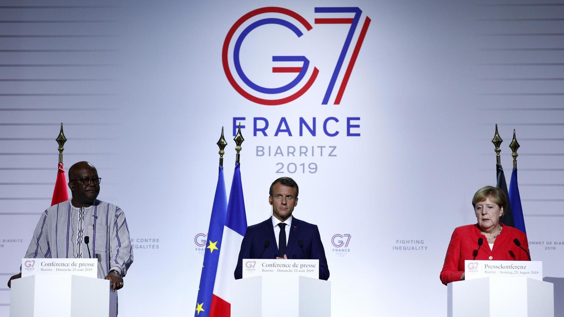 Bundeskanzlerin Angela Merkel (CDU), Roch Marc Christian Kabore, Präsident von Burkina Faso, und Emmanuel Macron, Präsident von Frankreich, geben eine Pressekonferenz im Rahmen des G7-Gipfels.