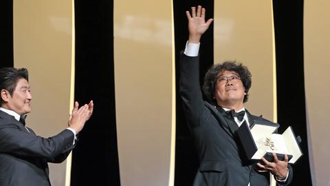 Bong Joon-ho (r.) posiert auf der Bühne beim 72. Cannes Filmfestival mit der Goldenen Palme.