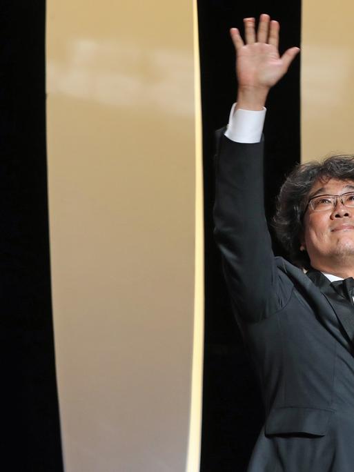 Bong Joon-ho (r.) posiert auf der Bühne beim 72. Cannes Filmfestival mit der Goldenen Palme.