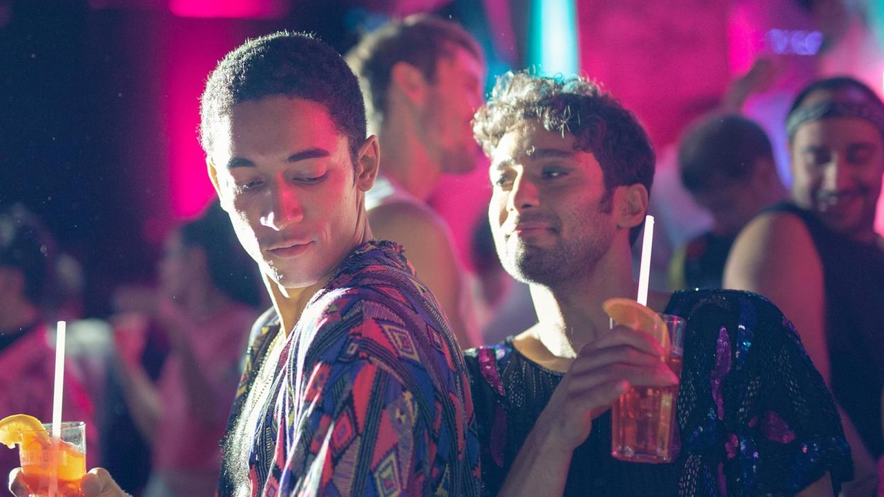 Zwei Männer trinken Cocktails, tanzen und flirten