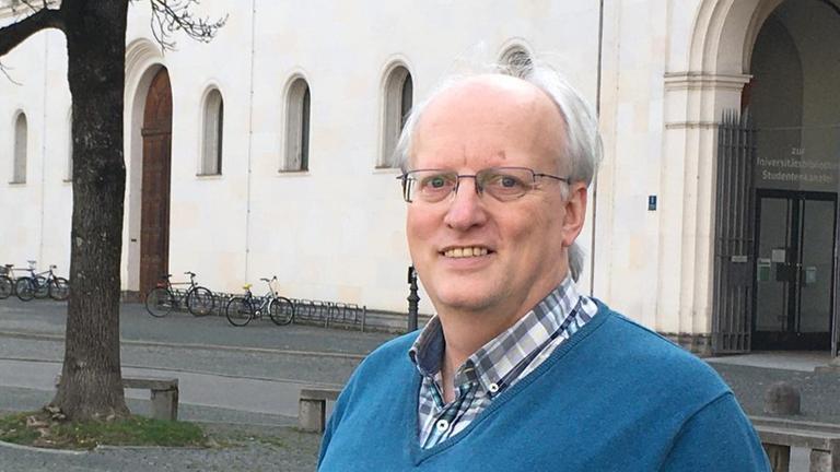 Helmut Zenz steht vor der katholischen Akademie Bayern und blickt freundlich in die Kamera