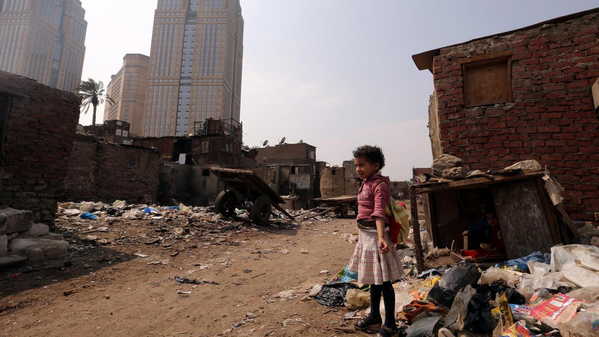 Ein Mädchen steht zwischen Müll in einem Slum vor Kairo.