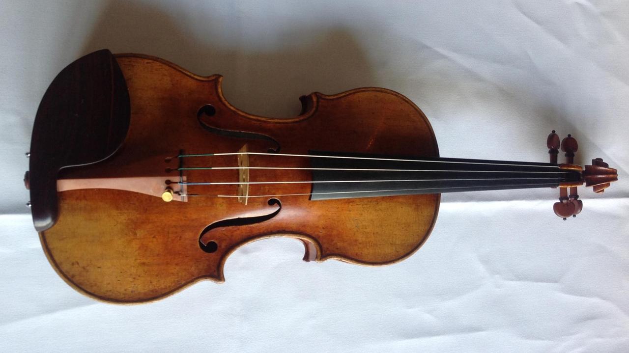 Die Stradivari-Geige liegt auf einem weißen Tischtuch.