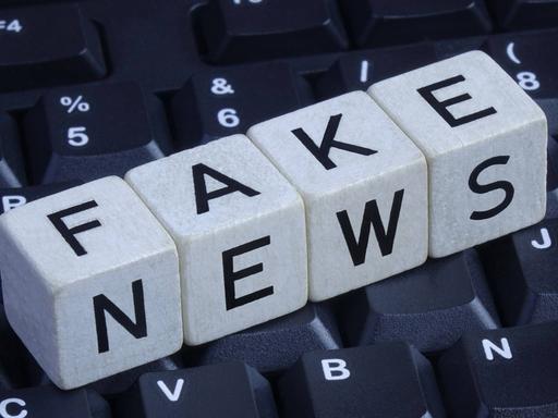 Würfel bilden den Schriftzug "Fake News" auf einer Computer-Tastatur.