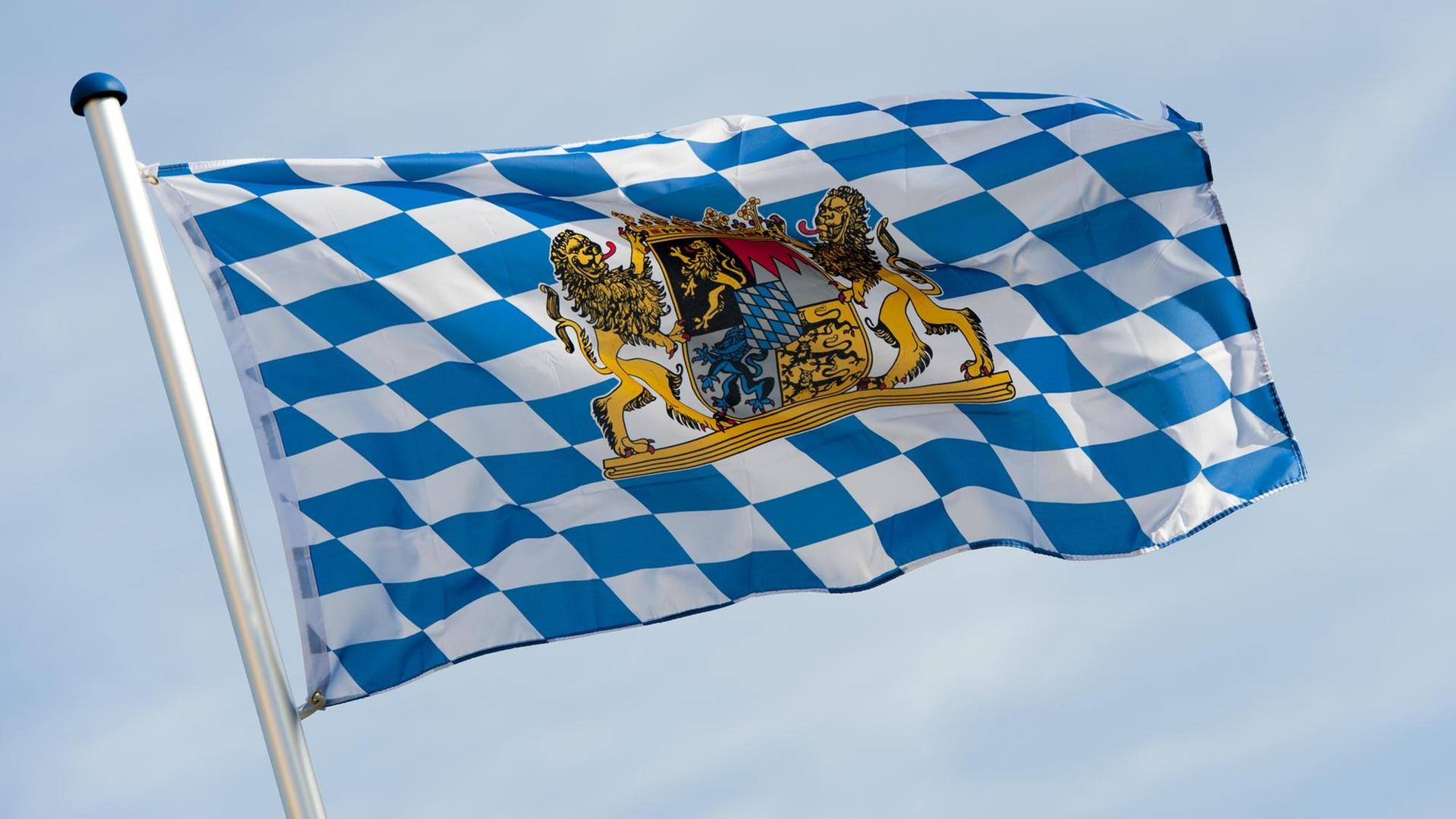 Ein weiß-blaue Bayernfahne mit Wappen weht im Wind.