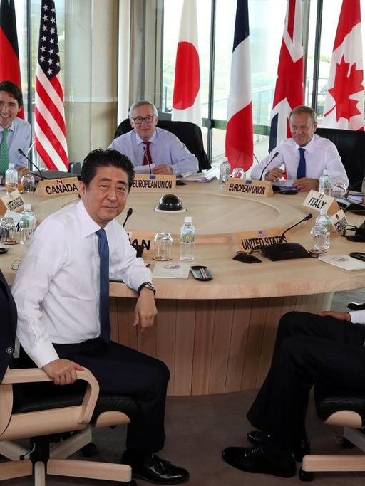 Die Staats- und Regierungschef der G7-Staaten sitzen gemeinsam an einem runden Tisch, Obama winkt in die Kamera.