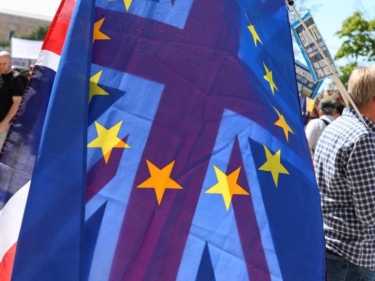 Ein Demonstrant mit einer EU- und einer britischen Flagge über der Schulter.