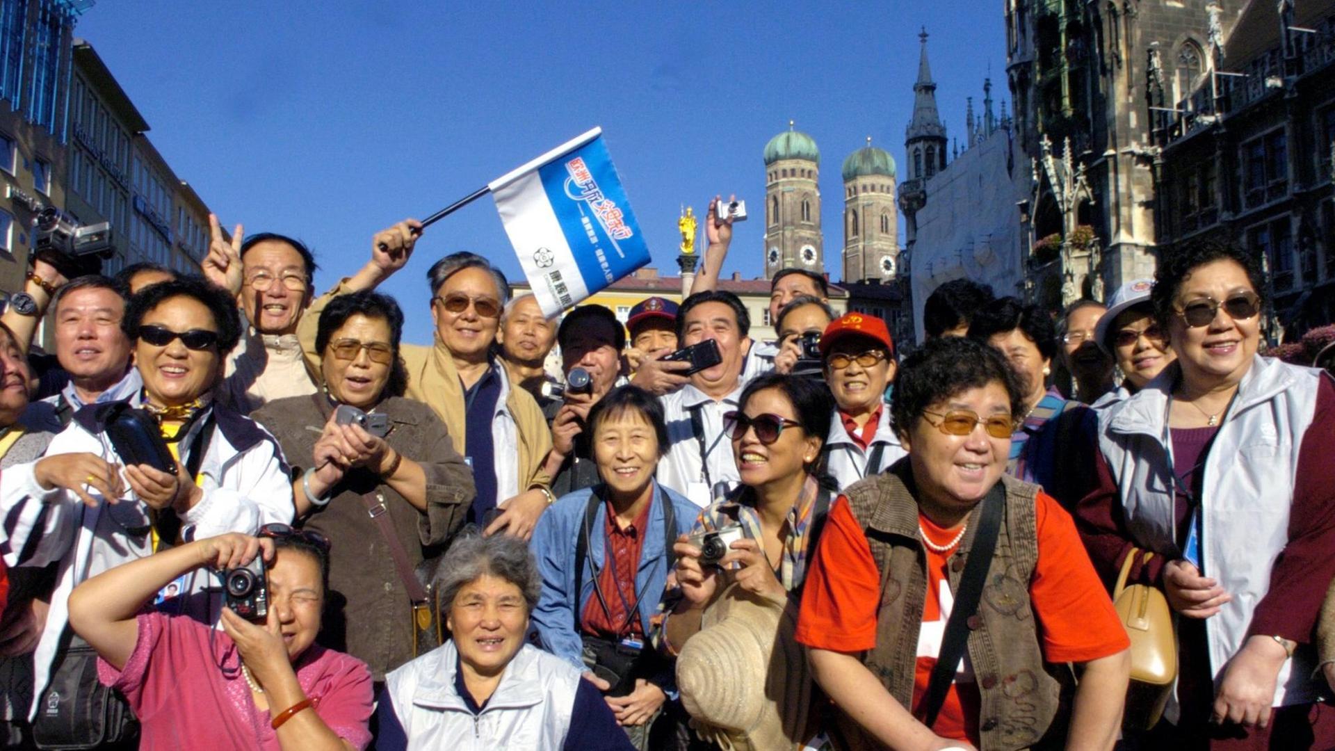 Chinesische Touristen posieren mit Fahne auf dem Marienplatz in München. Chinesische Touristen posieren mit Fahne auf dem Marienplatz in München.