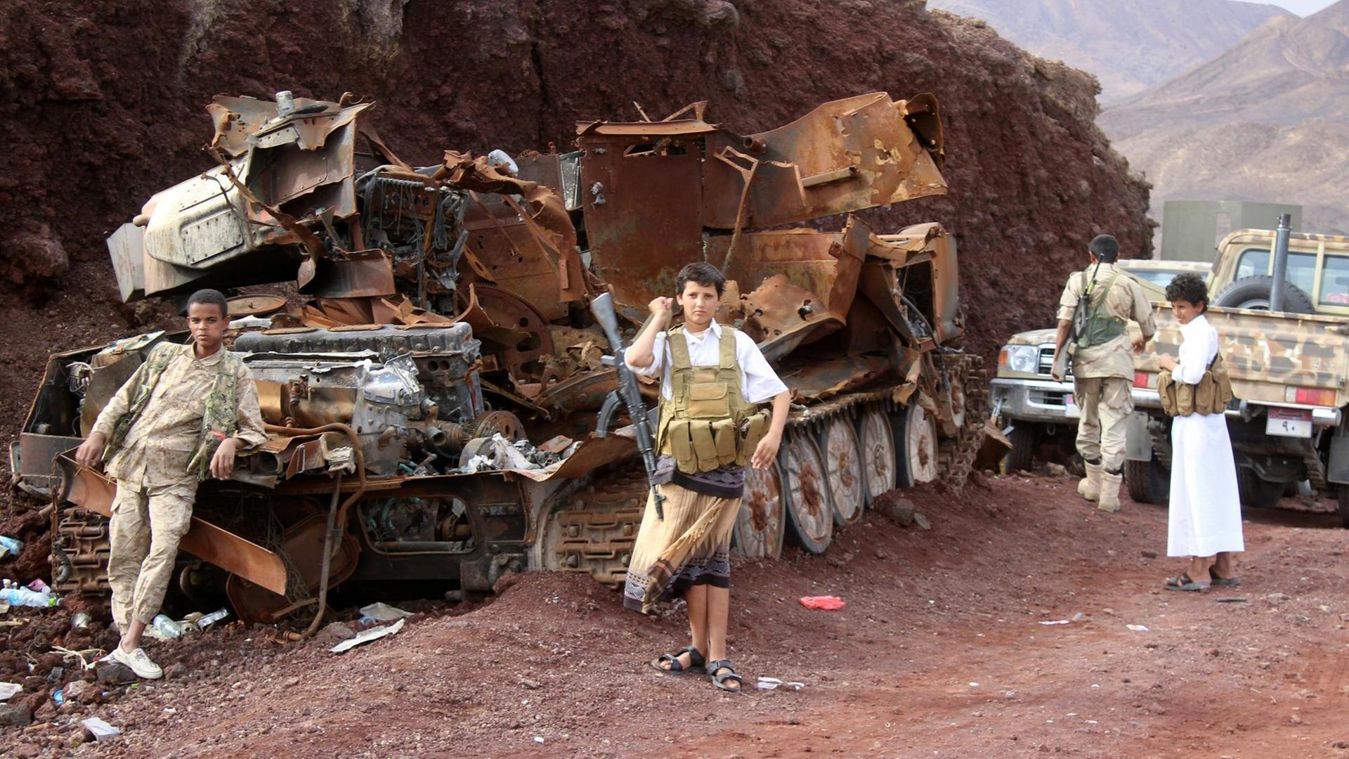 Jemenitische Kämpfer aufseiten des Präsident Abed-Rabbo Mansour Hadi stehen neben einem ausgebrannten Panzer in der Region Sirwah in der Provinz Marib.