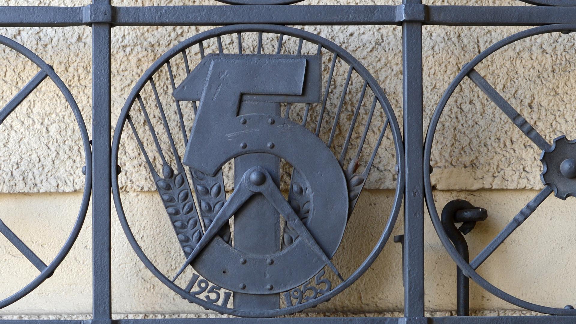 Emblem zum ersten Fünfjahresplan der DDR (1951-1955) in einem Tordurchgang in der Straße der Pariser Kommune in Berlin