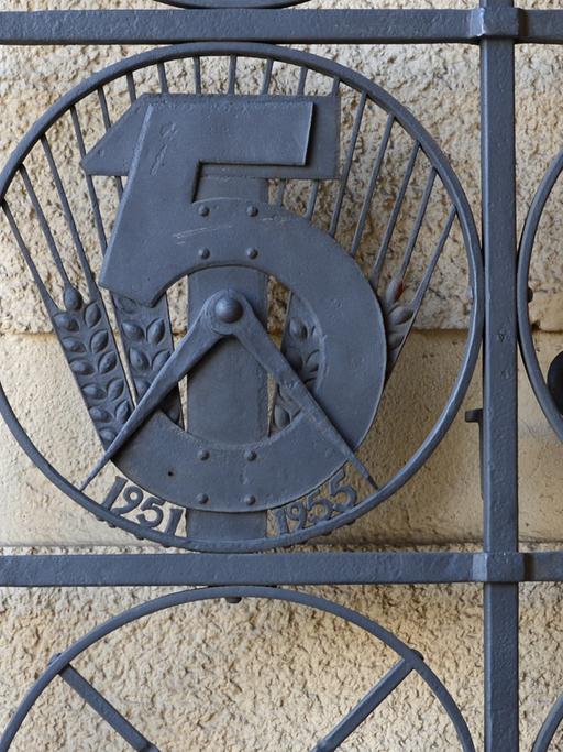 Emblem zum ersten Fünfjahresplan der DDR (1951-1955) in einem Tordurchgang in der Straße der Pariser Kommune in Berlin
