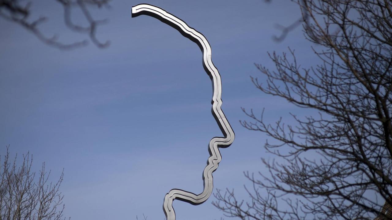 Eine Metallskulptur vor blauem Himmel, die scherenschnittartig die Form Georg Elsers Kopf nachbildet. 
