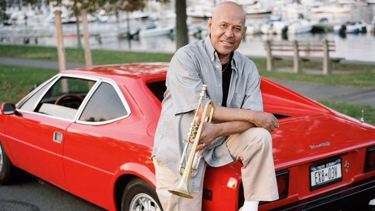 Der Jazz-Trompeter Eddie Henderson lehnt amn einem roten Sportwagen.