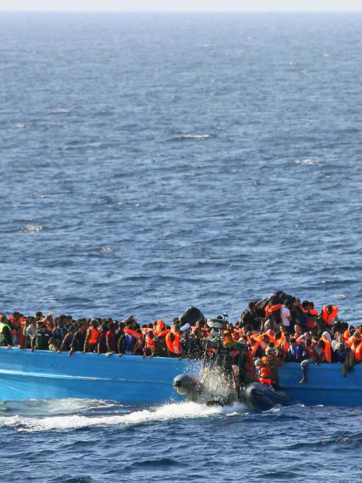 Bei Seegang rettet die Besatzung der deutschen Fregatte Schleswig-Holstein am 21.06.2015 rund 148 Kilometer nordwestlich vom libyschen Tripolis 417 Männer, 63 Frauen und 42 Kinder aus einem Holzboot und bringt diese zum Hafen von Salerno in Italien.