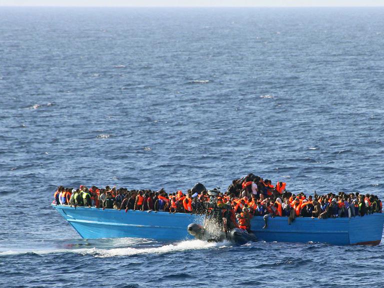 Bei Seegang rettet die Besatzung der deutschen Fregatte Schleswig-Holstein am 21.06.2015 rund 148 Kilometer nordwestlich vom libyschen Tripolis 417 Männer, 63 Frauen und 42 Kinder aus einem Holzboot und bringt diese zum Hafen von Salerno in Italien.